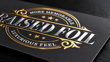 Close-up of smooth raised silver lettering and gold foil detailing on a black suede soft touch business card